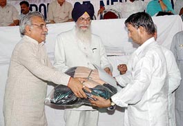 Governor of Tamil Nadu Surjit Singh Barnala, along with Chief Minister of Haryana Bhupinder Singh Hooda, gives relief material to a member of a terrorist victim family during the 93rd Shaheed Parivar Fund function organised by the Hind Samachar Group of Newspapers at Jalandhar on Sunday.