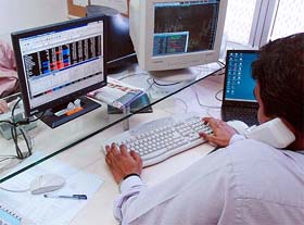 Brokers trade in stocks at the Bombay Stock Exchange on Monday as the BSE-30 index hit a historic high of 7,000.97 points