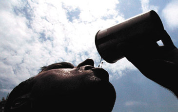 A worker quenches his thirst as heat wave conditions continued to scorch the city