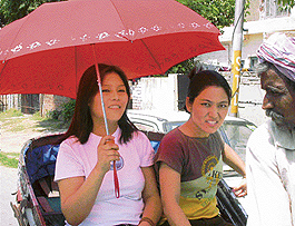 Braving the searing heat, these girls venture out with the protective covering of an  umbrella. The rickshaw puller, however, has  to sweat out in hot sun. 
