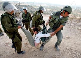 Israeli forces arrest a protester after she locked herself in a cage during a joint demonstration by Israeli, Palestinian and international peace activists, at the construction site of the controversial Israeli barrier in the West Bank village of Bilin on Wednesday