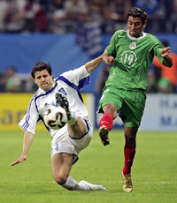 Panagiotis Fyssas of Greece challenges Alberto Medina of Mexico for the ball during their Confederations Cup soccer match at Frankfurt 