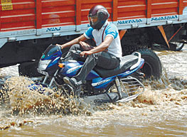 A motorcyclist tries to negotiate past a truck on a flooded street in the Model Town area of North Delhi on Friday morning.