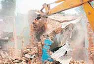 A JCB razes houses in Guru Nanak Colony in Mohali on Saturday