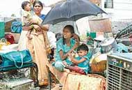 Homeless residents of the colony sit in the open after demolition of their houses