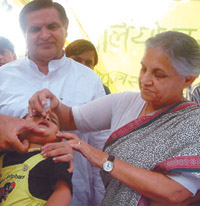 Delhi Chief Minister Sheila Dikshit administers polio drops to an infant at her residence on Saturday, ahead of the polio eradication drive that kicks off on Sunday, as Health Minister Yoganand Shastri looks on.