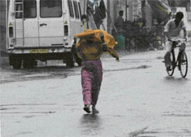 A woman takes shelter under her dupatta following a downpour in Ludhiana 