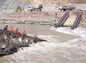 Rescue workers make their way along the remains of a temporary bridge across the Teesta at Ramvi village, some 700 km north of Kolkata