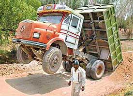 Front wheels of a dumper truck go up in the air as a result of overloading while tilting earth on a road in Chandigarh