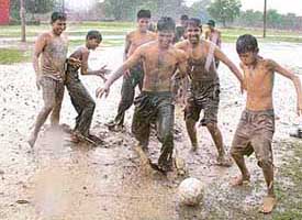 These spirited boys enjoy a game of football in the rain in 