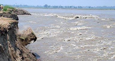 A chunk of earth falls into the Chenab off the bank near Akhnoor in Jammu on Friday.