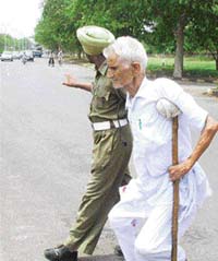 A Home Guard helps a physically challenged Sadhu Ram of Mubarakpur cross the road outside Government Medical College, Sector 32, in Chandigarh.