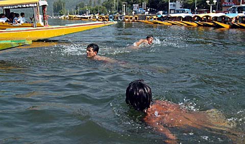 Youths enjoy swimming in the Dal Lake in Srinagar on Tuesday. Srinagar witnessed a sudden rise in temperature over the past one week with the maximum touching 37C this summer. 