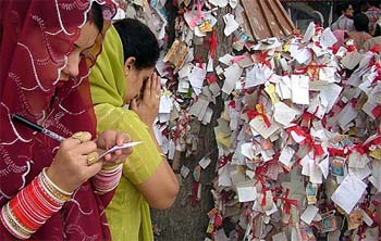 A newly-wed woman writes her wish on a piece of paper to be tied to a tree outside the 800-year-old temple of Nagdevta at Patnitop