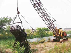 A drag line clears weed from Buddha Nullah near central jail in Ludhiana on Monday