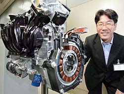 Japans auto giant Honda Motors engine researcher Tsuneo Tanai displays a cut model of the new hybrid engine system with a technology of variable valve timing and lift system which achieves 20 per cent power-up and more than 5 per cent of improved fuel economy from the current model at the companys headquarters in Tokyo on Tuesday.