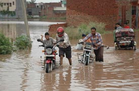 Stranded motorcyclists being helped by children to drag their vehicles out of knee-deep water in Zirakpur on Tuesday