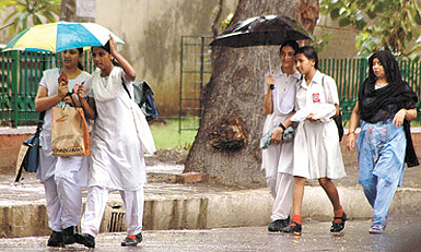 Children carry their schoolbags and umbrellas in the Capital on Tuesday. 