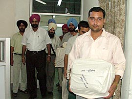 Vigilance officials come out of Baba Farid University of Health Sciences after seizure of the VCs computers in Faridkot on Tuesday.