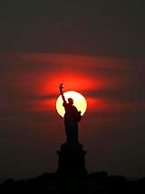 The sun sets behind the Statue of Liberty in New York on Tuesday