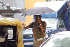 While a woman watches her step, a policeman tries to control the traffic in the heavy rain at Jantar Mantar in the Capital on Wednesday.