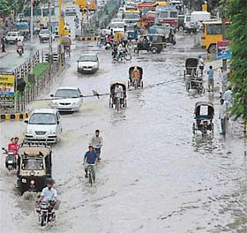 People wade through rainwater accumulated on the road near the bus stand, which was virtually converted into a lake following a downpour, in Jalandhar
