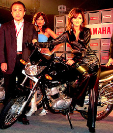 Chief Executive Officer and Managing Director of Yamaha Motors India Ltd. Hiroyuki Yanagi and models pose with a newly launched Yamaha G5 106cc motorbike in New Delhi on Thursday.  The motorbike is available in four colours at a base price of Rs 40,990.