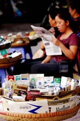A Vietnamese vendor reads a newspaper while she displays cigarettes for sale at a street in Hanoi, Vietnam, on Friday.