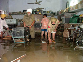 Policemen shift records from a submerged room at the Civil Lines police station following incessant rain in Bathinda on Friday.