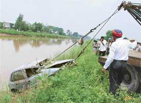 Policemen pull out the car from which the bodies of three women were found on Saturday