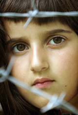 A girl looks through barbed wire as Bosnian Muslims attend the reopening ceremony of a reconstructed mosque at the Gornji Potocari village near a memorial centre for Srebrenica victims on Sunday