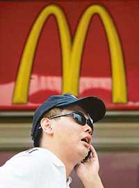 A Chinese man uses his mobile phone outside a branch of US fast food giant McDonald's in Beijing