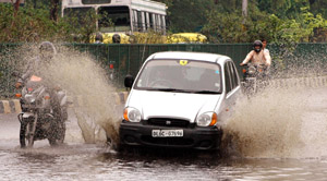 A car splashes through a waterlogged road in the Capital