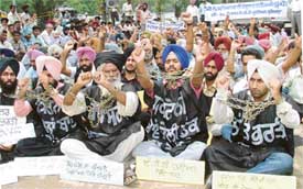 Dressed in black clothes and in chains, unemployed ETT teachers stage a protest against the Punjab Government on the Ferozepore road in Ludhiana