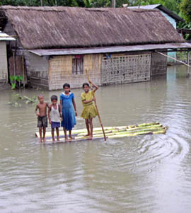 Children float on a makeshift raft in front of their flooded house in Garsinga village, about 250 km North of Guwahati on Sunday. Torrential rains lashed North-East on Sunday, causing heavy flooding that killed at least 12 persons and left more than 100,000 homeless.
