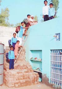 Students scale a house to reach their school at Balluana village near Abohar as the school remained cut off from the road for past 15 days due to accumulation of rainwater. 