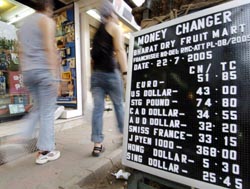 Pedestrians walk past a board displaying currency prices in New Delhi on Friday. The value of Indian rupee to the US dollar shot to its highest level in nearly six years at 43.20 rupees during the days trading amid expectations that the higher yuan value will give an edge to Indian exports over Chinese rivals. 