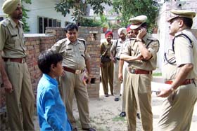 Police officials talk to a boy who was playing nearby at the time of robbery in the PSEB office in Bathinda