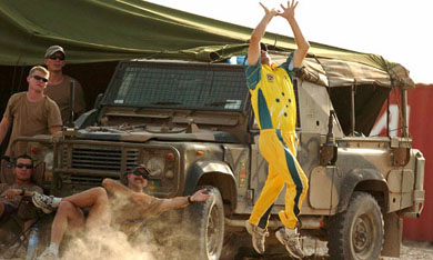 An Australian soldier jumps to take a catch in front of an army vehicle during a cricket match against the British soldiers in Al Muthanna