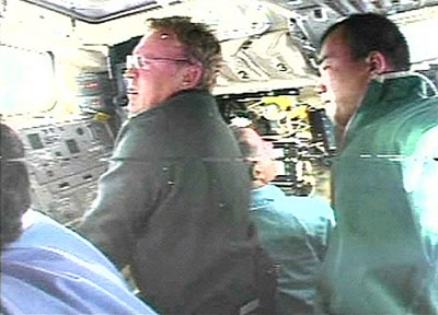 Astronauts Andy Thomas of Australia and Soichi Noguchi of Japan work with the shuttle Discovery's robotic arm orbital boom sensor system as they prepare to inspect the shuttle's nose and wing leading edges 