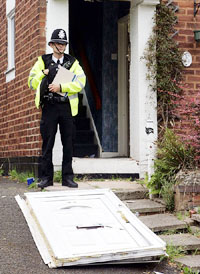 A police officer guards a house in the Washwood Heath area of Birmingham, central England, as it is searched in connection with investigations into the London bombings on Wednesday