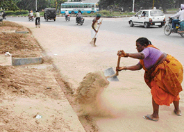 a woman removes mud from a sewer path near Piccadilly Chowk