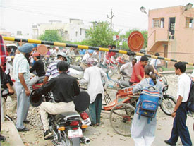 Commuters try to pass through the level crossing by manually lifting the barrier that remained closed for over one hour