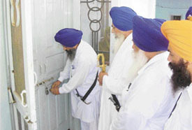 Baba Balwant Singh Nandgarh gets the two locks opened at the door of Devan Sahib at the gurdwara at Bhoju Patti, Barundi