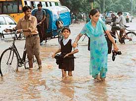 A mother helps her daughter wade through water to reach home after school in Sector 45.