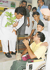 A volunteer of the Vatavaran Sambhal Society gifts a sapling to a physically challenged man in Ludhiana on Wednesday.