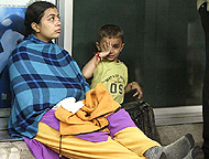 Survivors Rashmi Bhavsar and her son Tarana sit outside the terminal building after the crash of an Air France jet in Toronto 