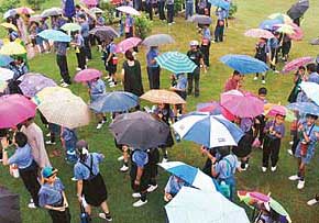 Students of The Gurukul protect themselves against rain with umbrellas during a function at Model Park, Sector 20, Panchkula, on Thursday.