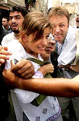 United Nations workers Christine Blunt of Britain and Steven Karl of Switzerland are escorted by security officers after being freed from kidnappers in the Gaza Strip on Monday