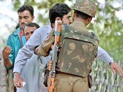BSF jawan frisks pedestrians on the Sheerwani road in Srinagar on Tuesday. 
